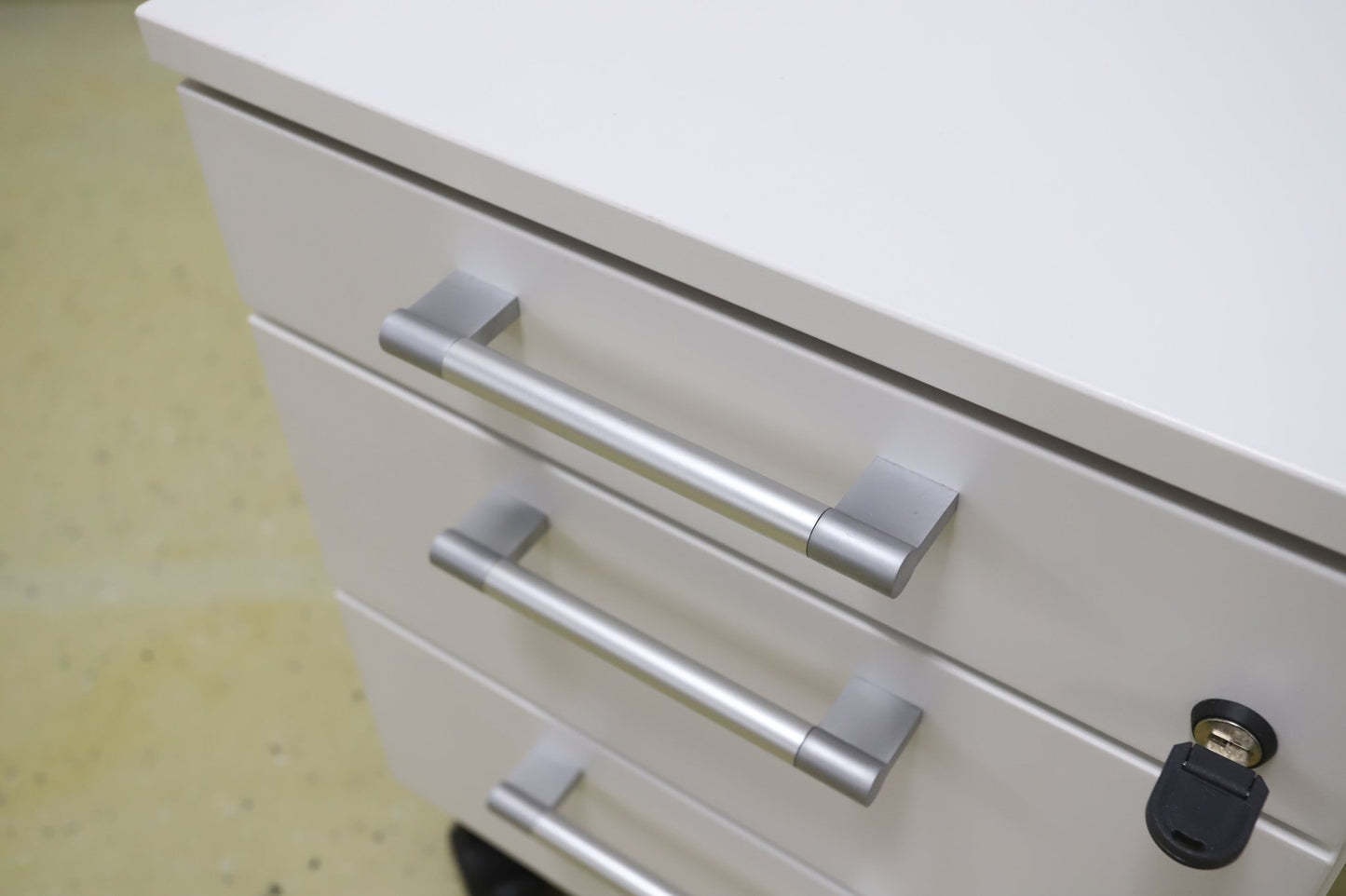 Lukittava kolmeosainen valkoinen laatikosto, harmaat kahvat - Suomen Kalustekeskus